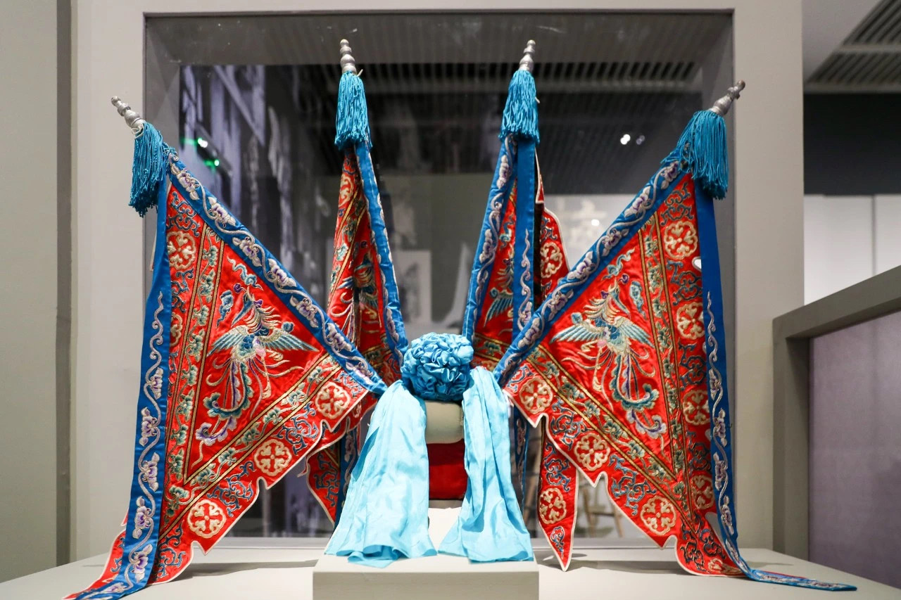 Ornate Qing dynasty Peking opera flag helmet with phoenix embroidery on red silk, displayed at National Museum of China Mei Lanfang exhibition