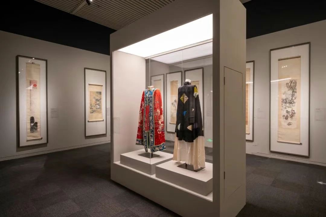 Museum gallery display featuring traditional Chinese costumes and scrolls illuminated by museum track lighting at Mei Lanfang exhibition