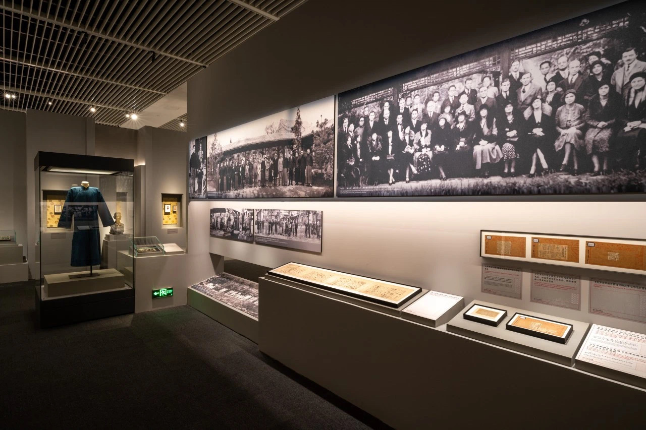 Museum exhibition display case with Peking opera costume and historical photographs, professionally lit by museum track lighting system at National Museum of China