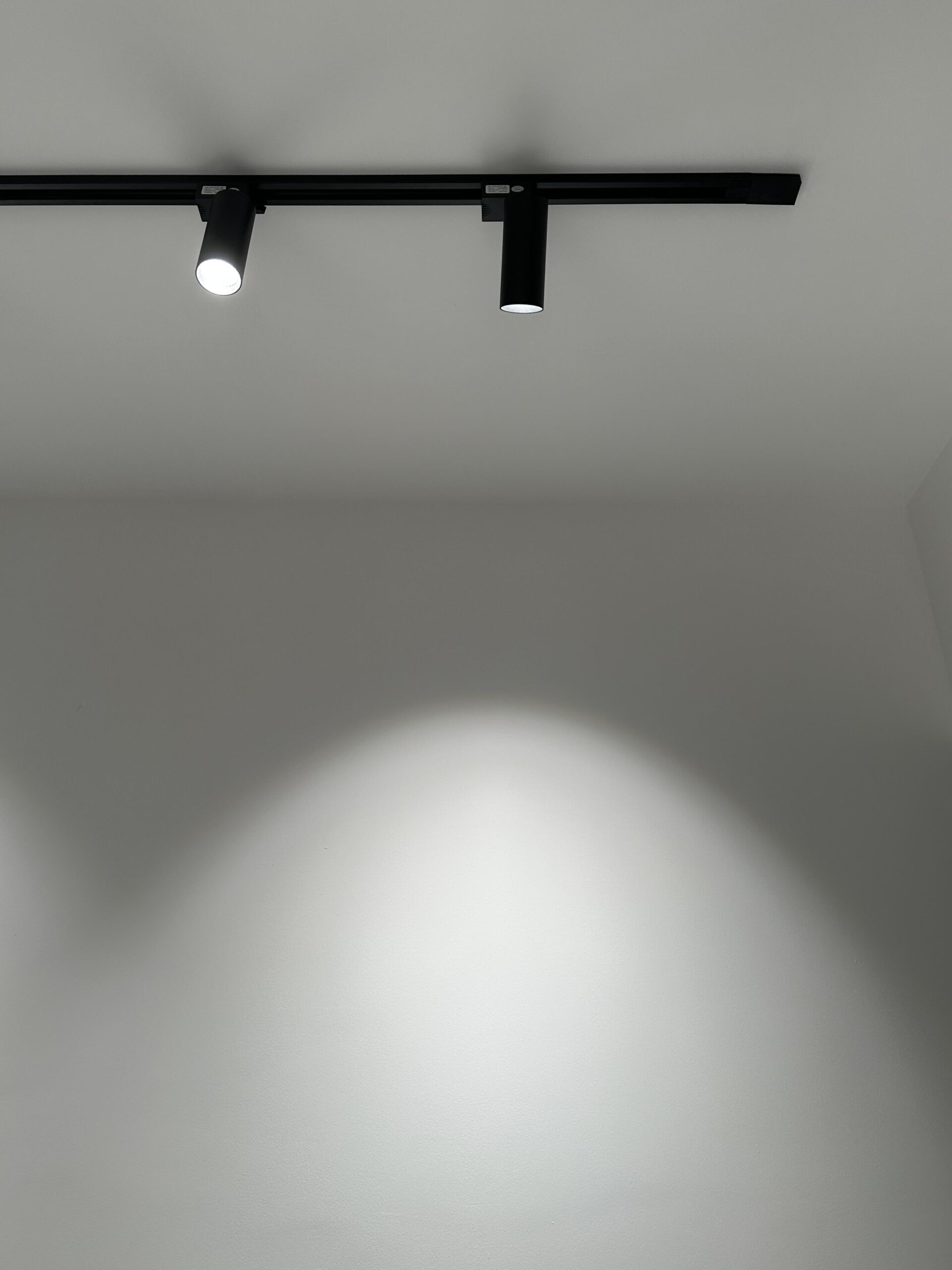 Close-up of cylindrical black track light head adjustable on rail system - showing installation detail