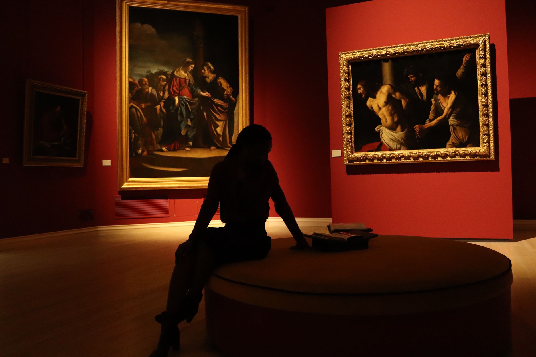 Museum gallery paintings illuminated by precise gallery track lighting in a dimmed exhibition hall