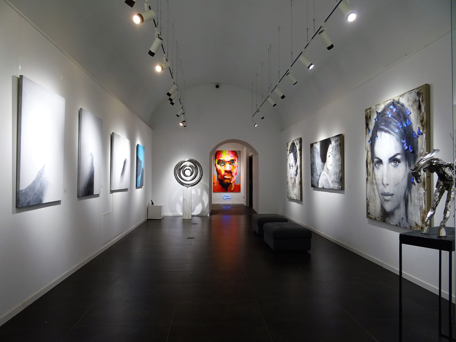 Modern art gallery with track lighting directing focused beams onto contemporary paintings