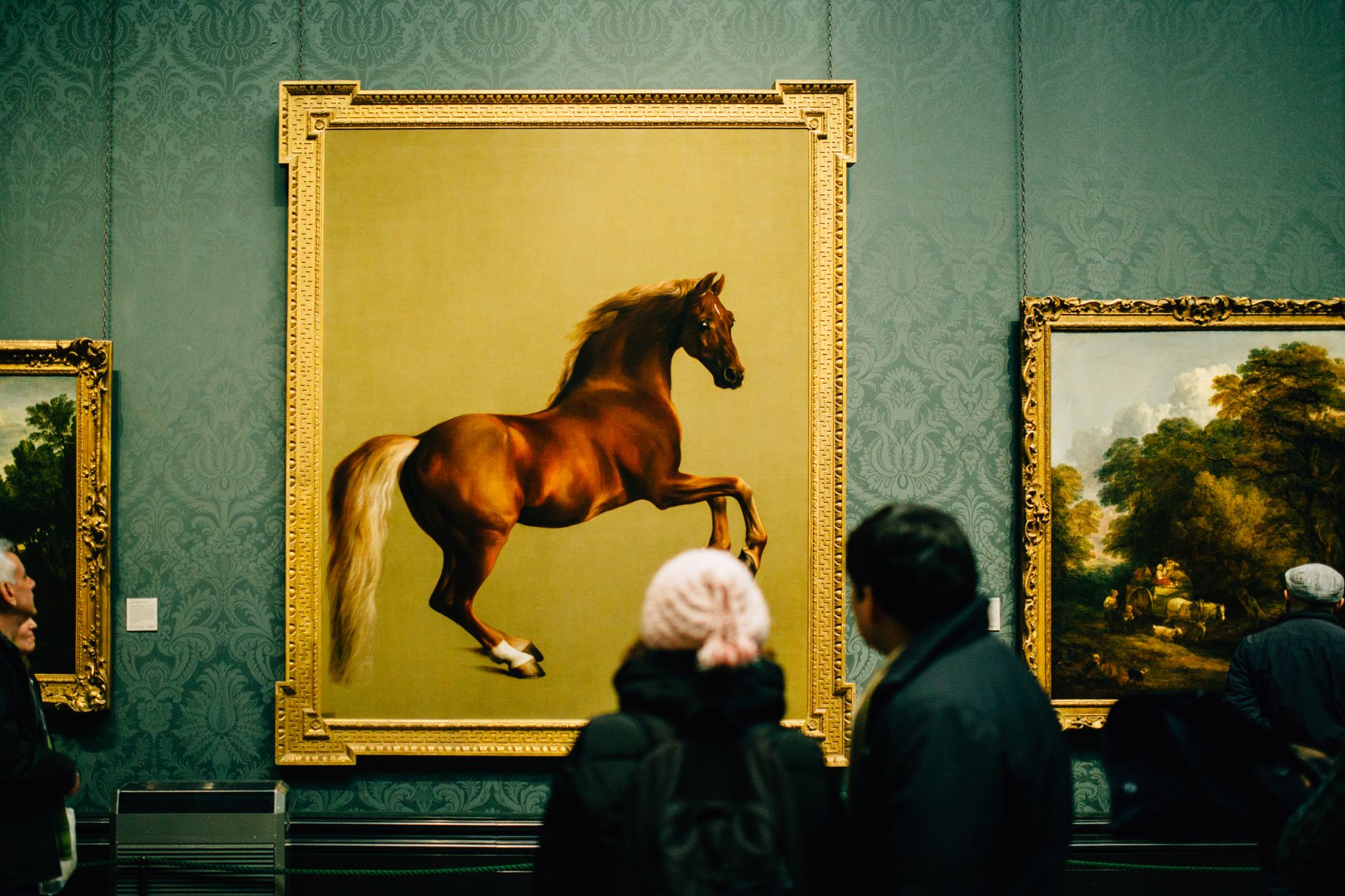 People pausing to view a single artwork lit by a focused display spotlight, showing how focused light creates a hero focal point