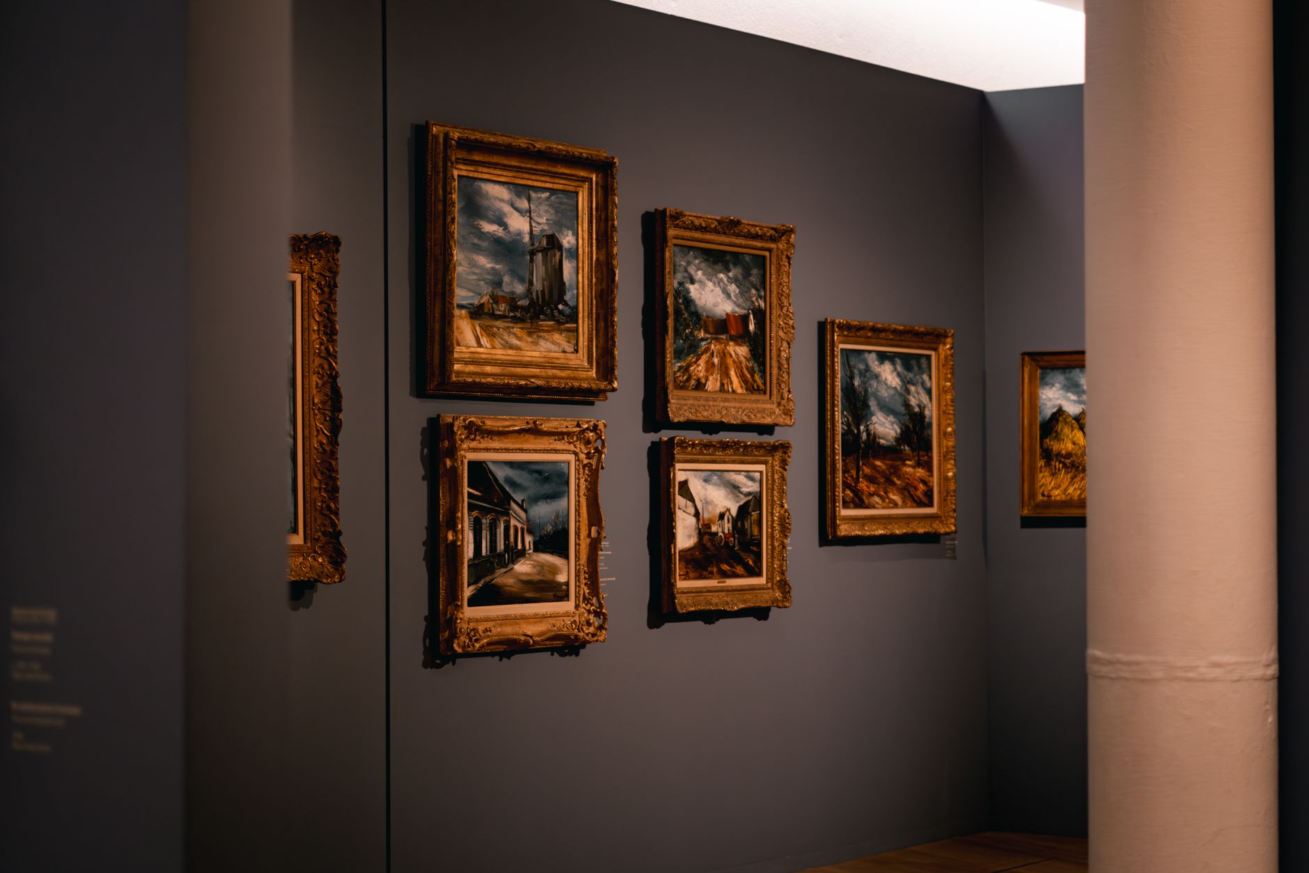 Classic framed paintings displayed on a dimly lit museum wall under conservation-safe track lighting