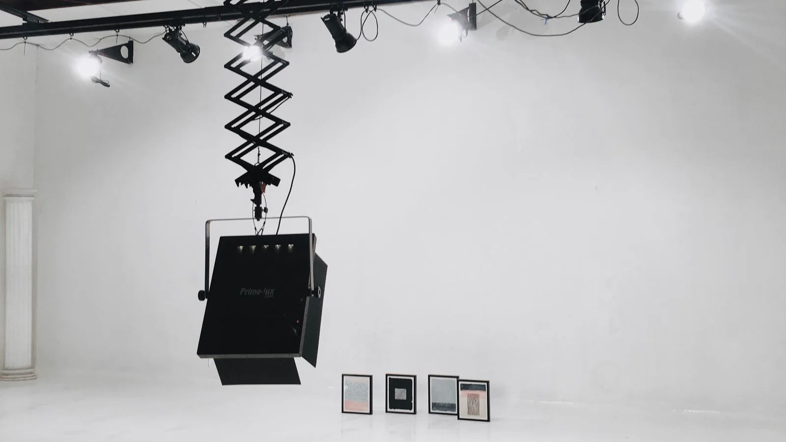Lux vs lumens lighting metric diagram shown in a contemporary art gallery with LED track lighting on a painting