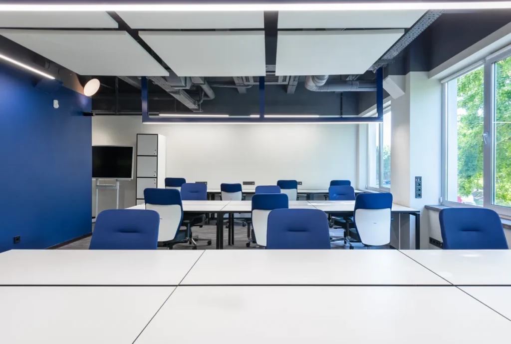 Modern office meeting room with suspended linear LED track lighting across the ceiling for workplace illumination