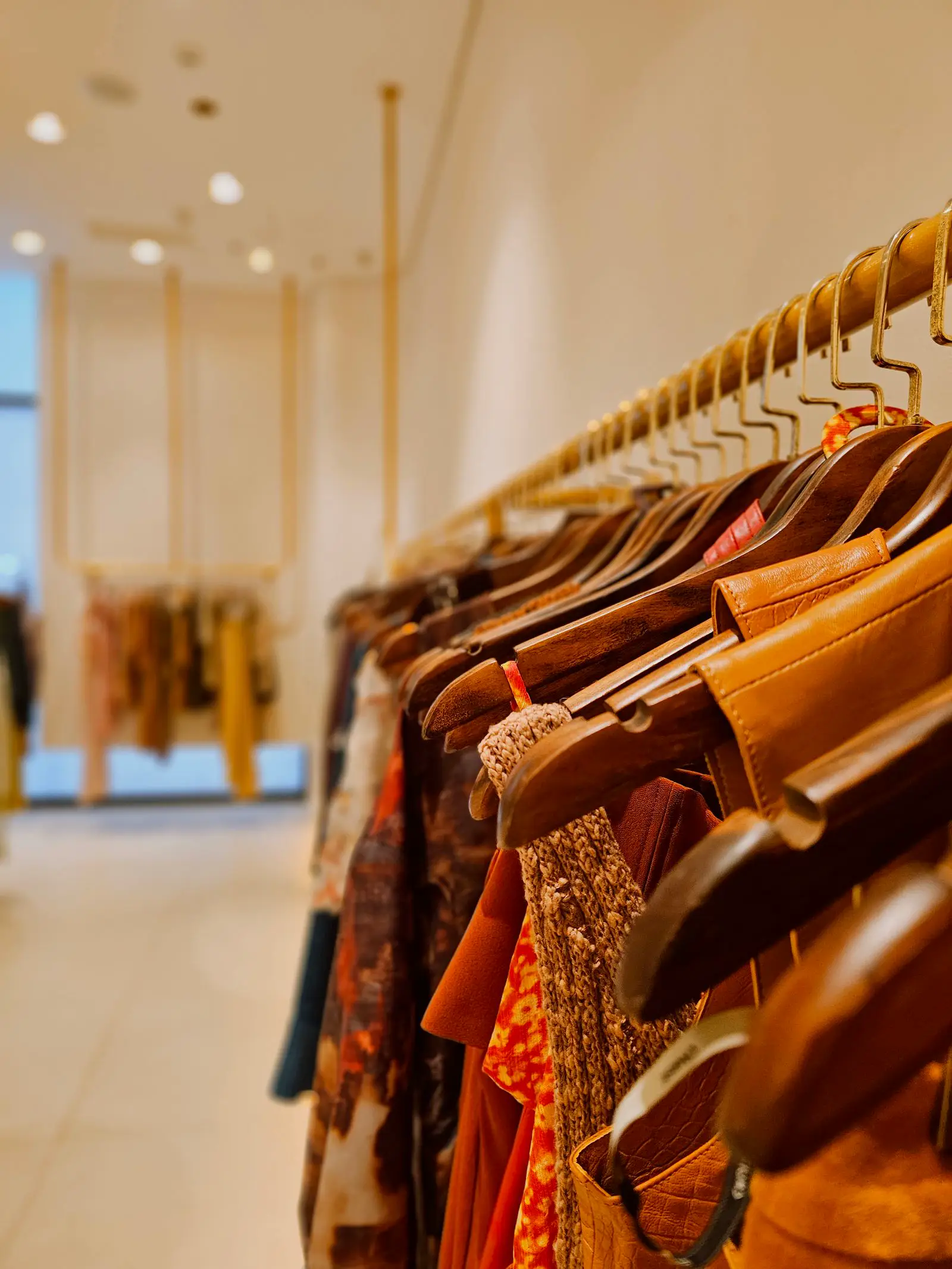 Modern fashion store with wooden hangers and warm display lighting at 500 to 1000 lux on merchandise