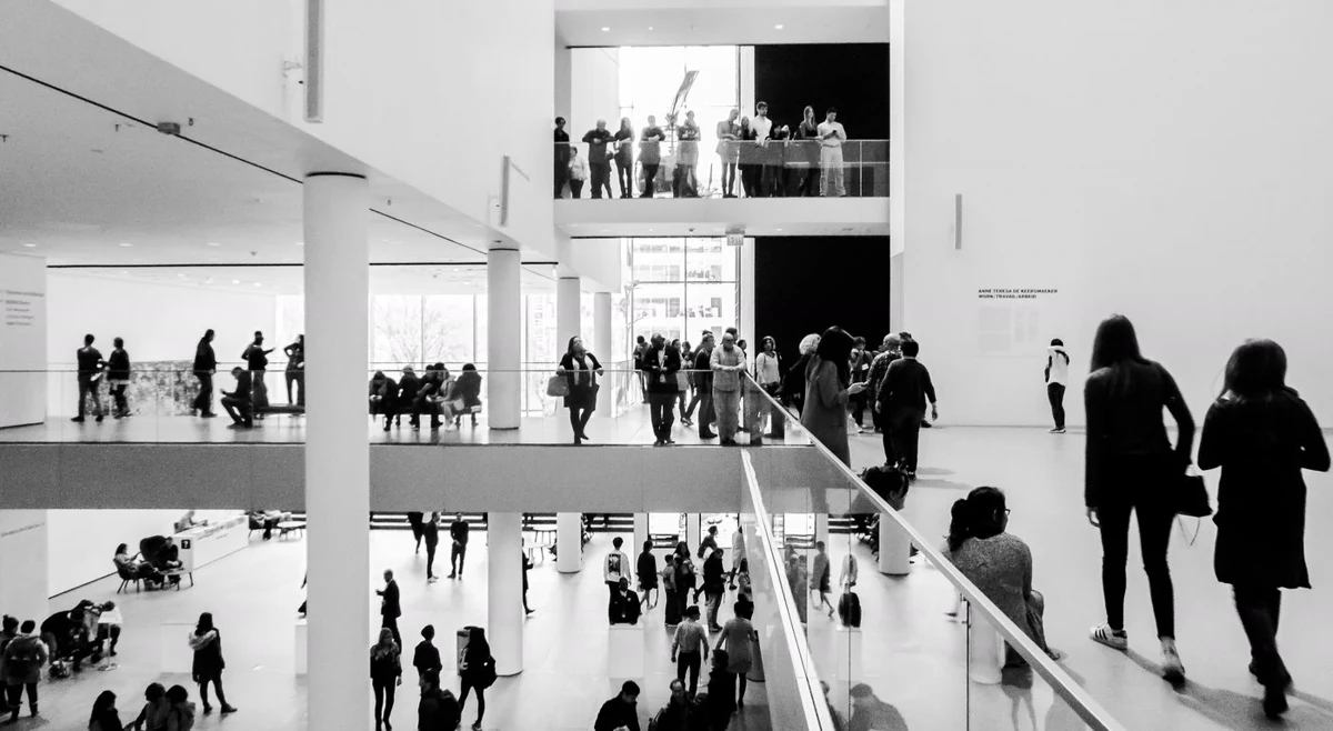 Bright multi-level museum atrium in New York with white walls and track heads above the gallery edge