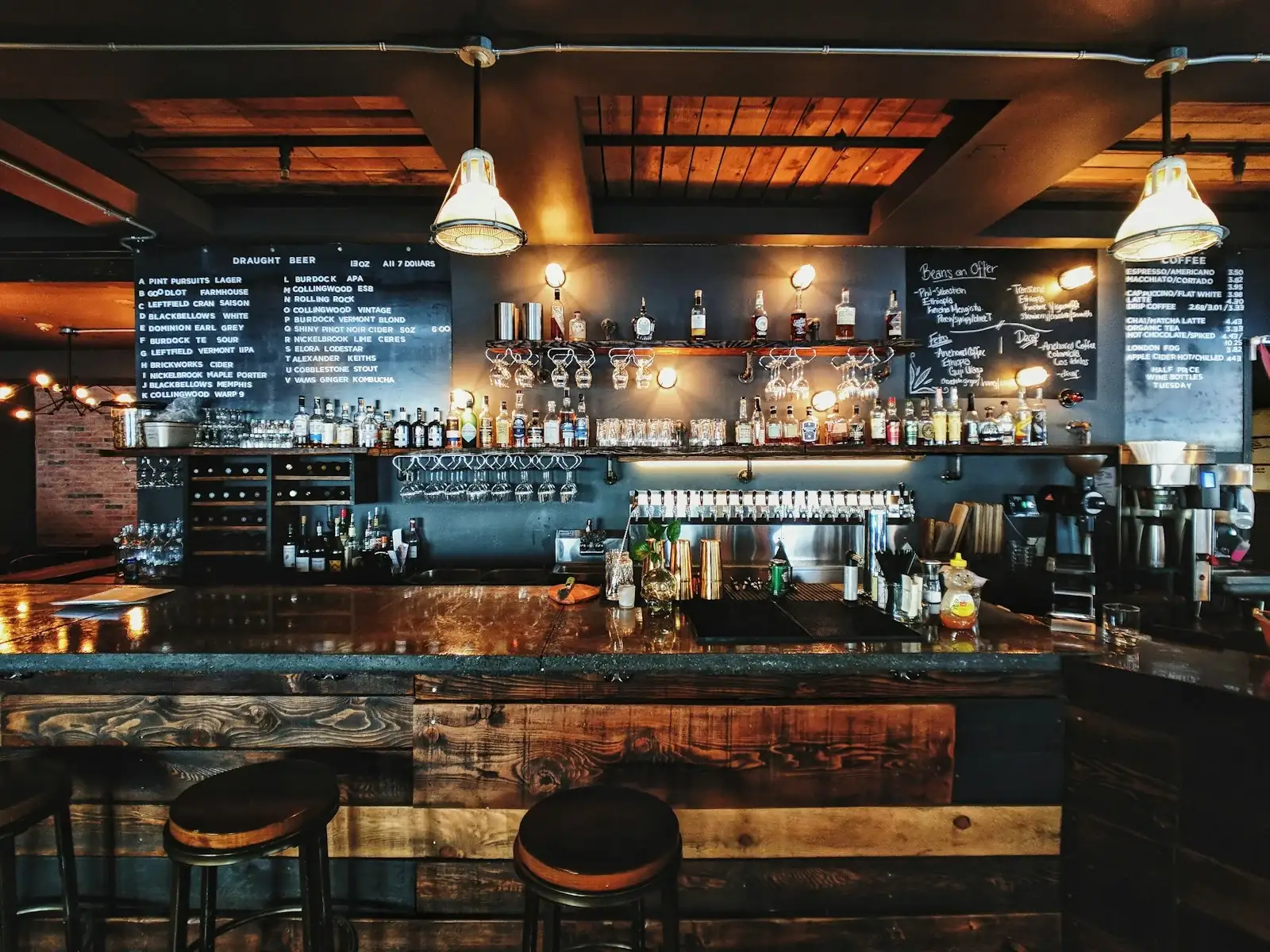 Restaurant bar counter with pendant lights over the bar top at 3000K showing pendant row spacing above a bar counter