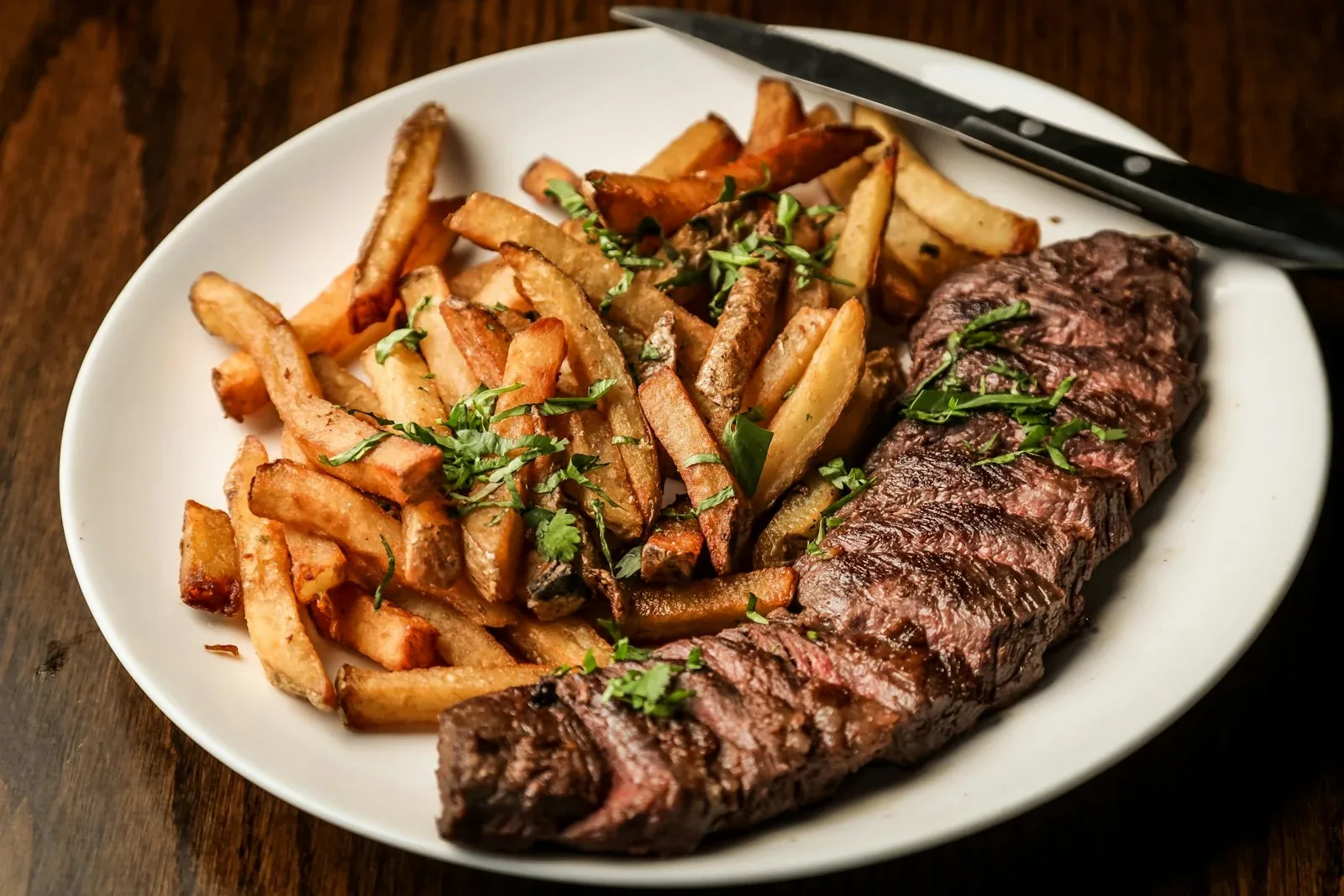 Grilled steak and rosemary fries plated under warm restaurant lighting demonstrating high CRI and R9 colour rendering on red meat