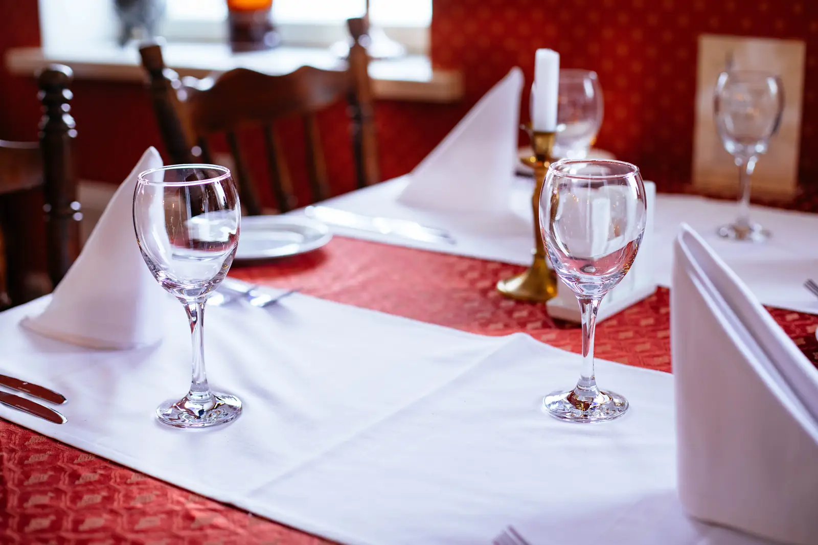 Restaurant table setting at 2700K with red wine glasses and a candle, showing the deep red rendering and the low ambient level of a dinner service scene
