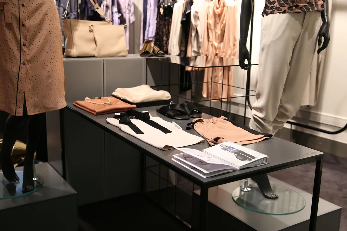 Menswear table presentation with folded garments lit from above by adjustable retail display lighting track heads