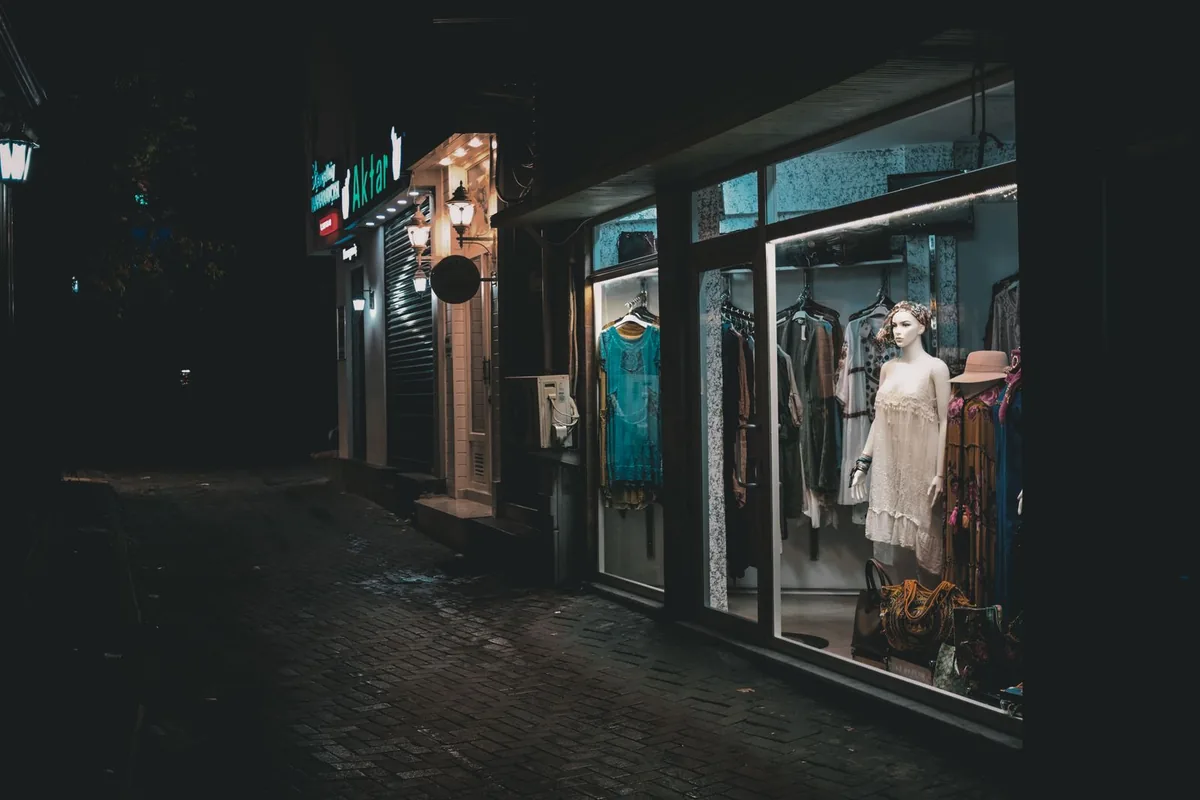 Retail shop window display at night lit by track lighting against a dark street, showing why window lighting needs its own dimming circuit