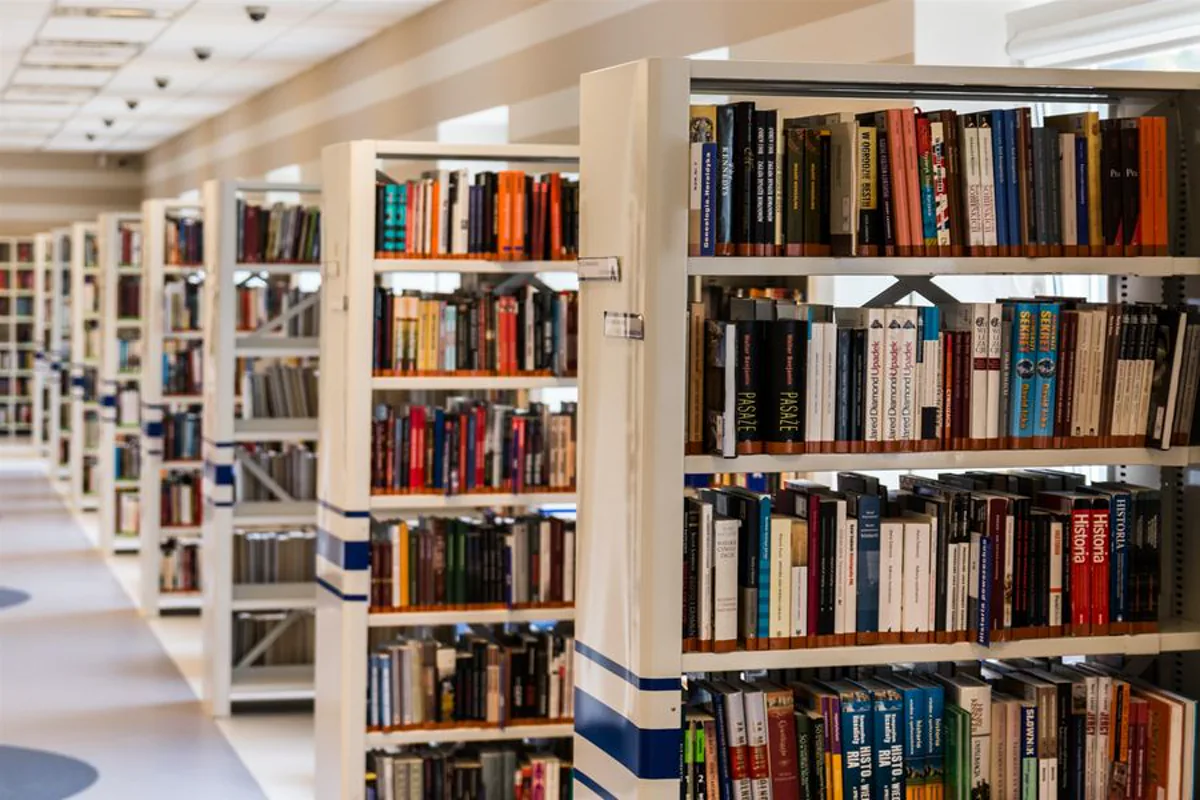 University library aisle lit by continuous linear LED lighting that keeps shelves and reading tables evenly illuminated