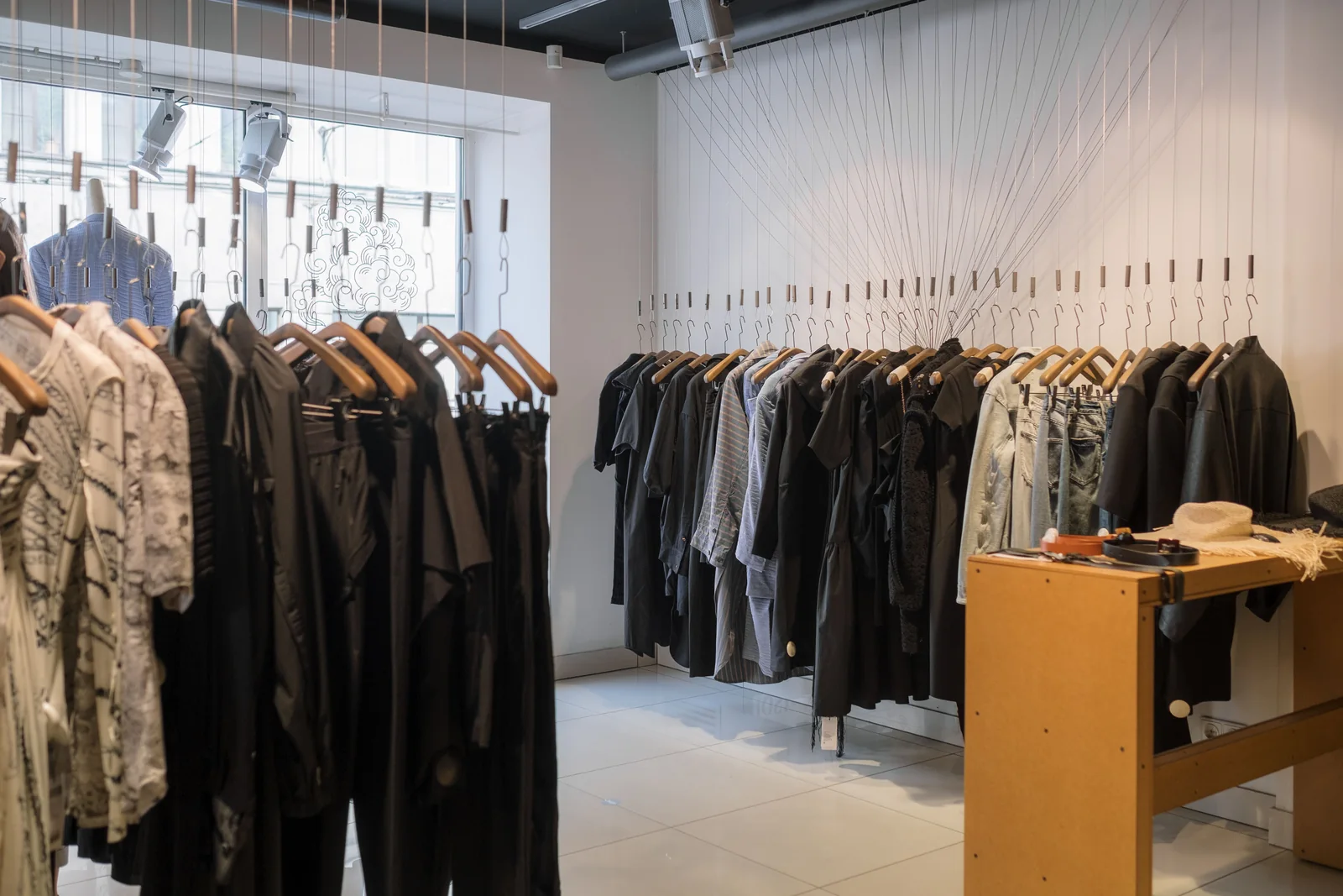 Clothing store aisle with a long track run down the ceiling lighting rails of garments on both walls