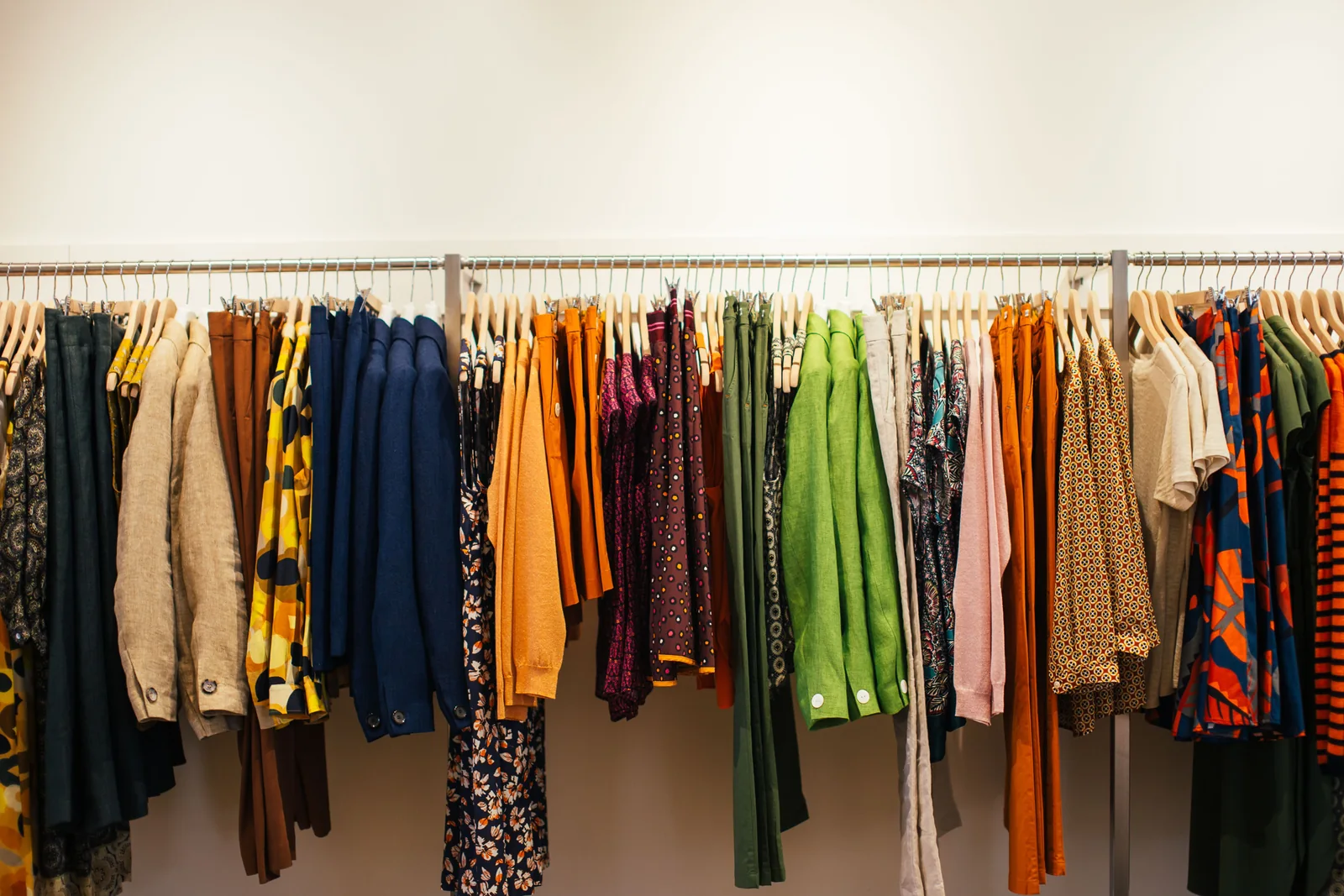Rail of multicoloured garments photographed side-on showing how an even vertical wall wash keeps every colour reading at full saturation