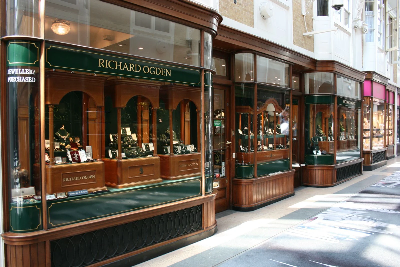 Historic jewelry store shopfront with warm lit vitrines behind glass, showing how a jewelry store relies on aimed display lighting rather than general light
