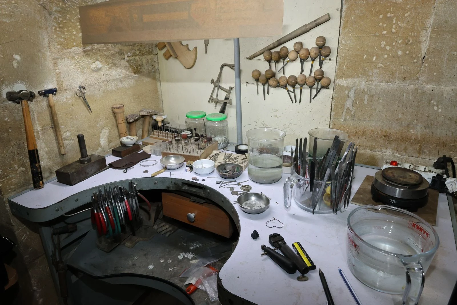Jeweler's workbench with hand tools and a loupe, the kind of bench that needs the same high CRI task lighting as the retail counter