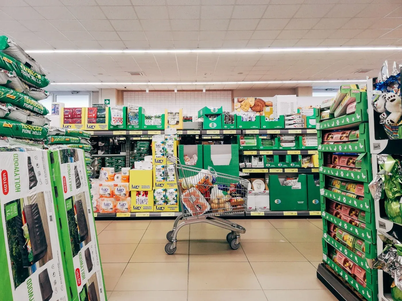 Supermarket aisle run under track and linear lighting, showing a shopping cart, 2.40 m clear aisle and shelf faces lit from above
