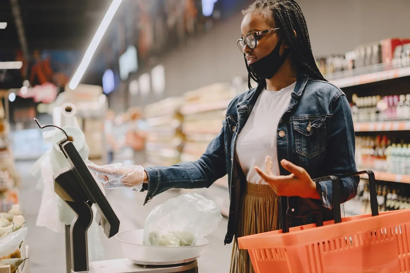 Customer weighing fresh vegetables on a digital scale at a supermarket service point, a task area that needs 500 to 750 lux directly on the display